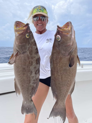 blonde woman holding two large fish