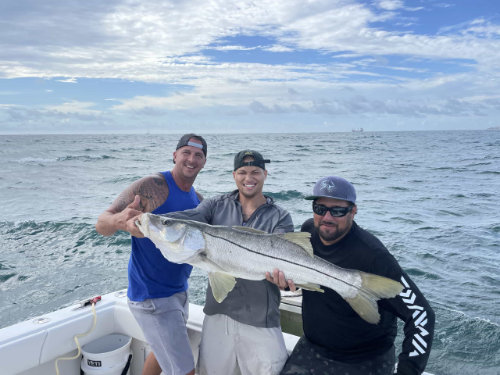 three men holding a large fish