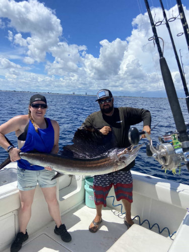 Two people holding a long fish